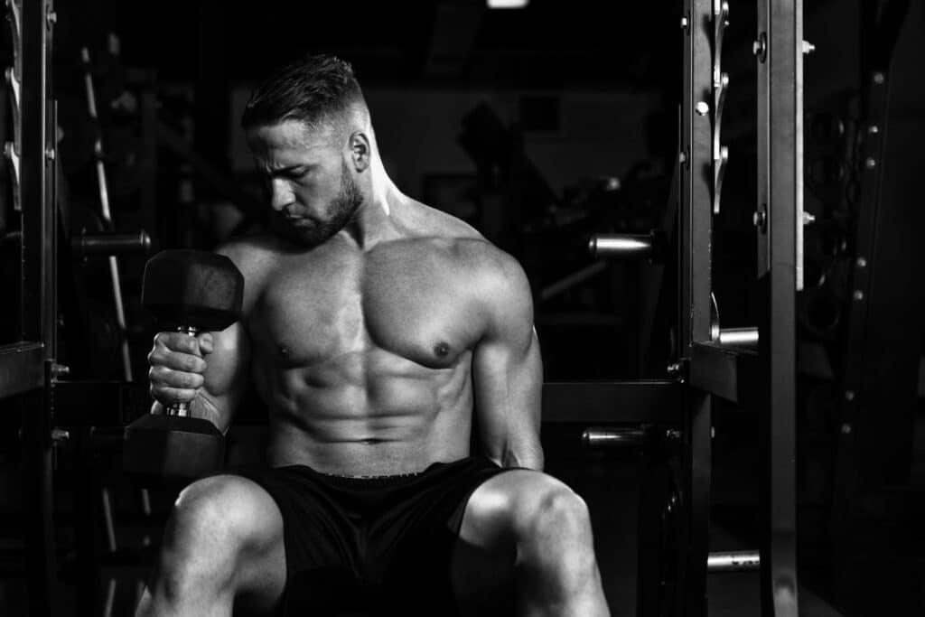 Férfi edzés közben súlyzót emel, a Stanozolol hatása révén látható izomdefinícióval és erővel.